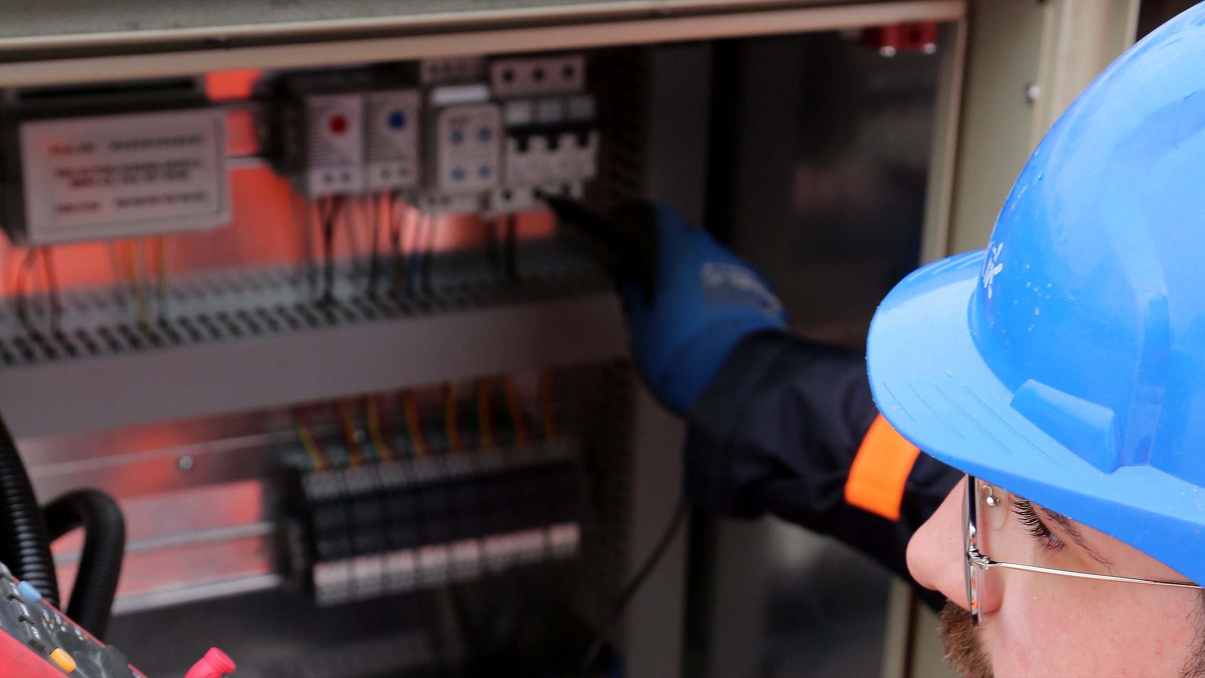 Técnico con casco revisando un cuadro eléctrico en una instalación